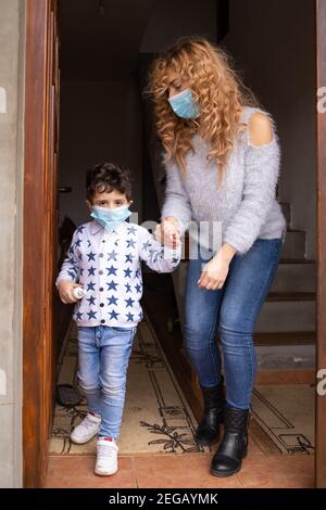 Mom and her toddler son wearing face masks getting ready to go out Stock Photo