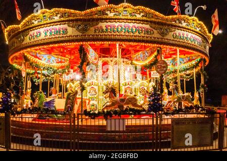 A traditional fairground carousel lit up at night on the South Bank, London, UK