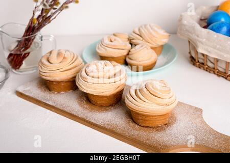 cruffins easter spring pastries, a mixture of muffin and croissant on a light background, the composition Easter painted eggs willow and cake. Stock Photo