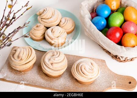 cruffins easter spring pastries, a mixture of muffin and croissant on a light background, the composition Easter painted eggs willow and cake. Stock Photo