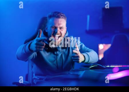Happy male gamer playing online video games in cyber cafe. Stock Photo