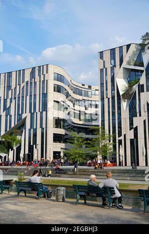 'Kö-Bogen' buildings, designed by New York star architect Daniel Libeskind, completed in 2013. People sitting on benches and enjoying the nice weather. Stock Photo