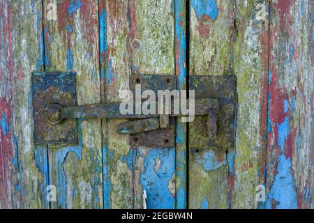 Close up view of an old metal door latch on a barn door with peeling paint Stock Photo