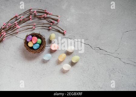 Colourful Easter eggs in bird's nest with decorative willow branches on gray cement background Stock Photo