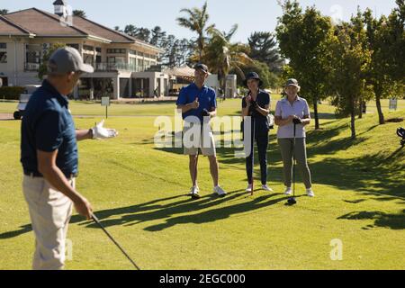 Three caucasian senior men and women watching man preparing for a shot on the green Stock Photo