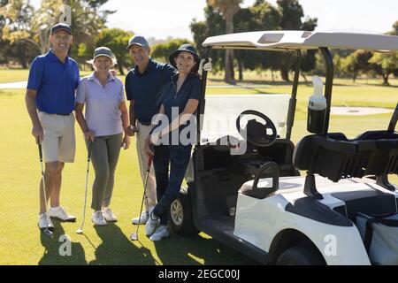 Four caucasian senior men and women standing by golf buggy looking at the camera and smiling Stock Photo