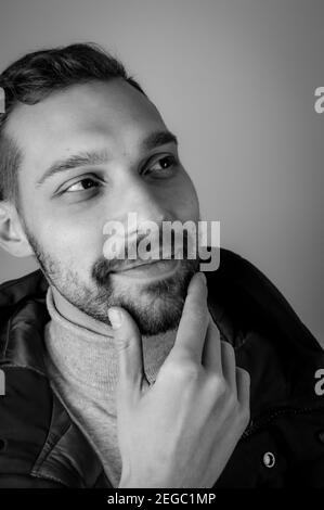 Black and white portrait of a young man touching his chin in a moment of inspiration Stock Photo