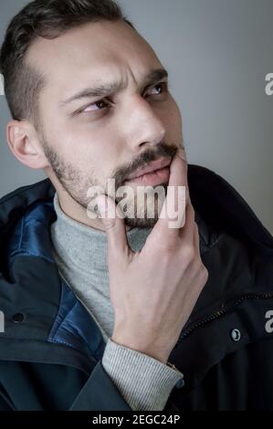 Portrait of a young man touching his chin in a moment of doubt or reflection Stock Photo