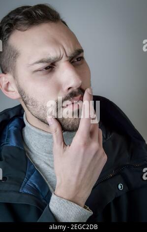 Portrait of a young man touching his chin in a moment of doubt or reflection Stock Photo