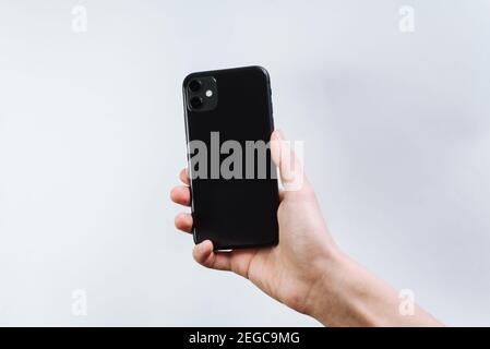 Samara Russia - 04.05.2020: A young man holding in a smartphone in hand. The back of the iPhone 11, 2 cameras. Customer holding the Iphone 11 black in Stock Photo
