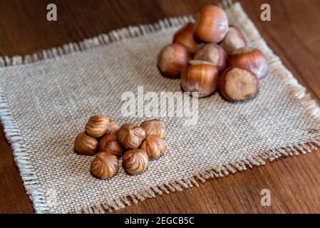 Peeled hazelnuts and hazelnuts in shell on rustic wooden table Stock Photo