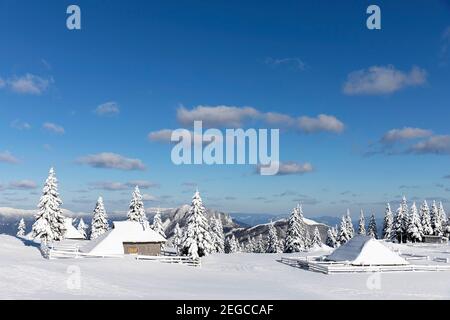 Idyllic old wooden alpine hut covered with snow in the mountain landscape of popular hiking destination Velika planina, Slovenia Stock Photo