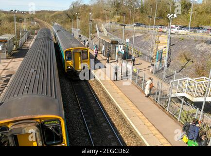 Llanharan, Wales - April 2018: Passengers waiting on the platform at Llanharan railway station near Cardiff as a commuter train pulls into the station Stock Photo