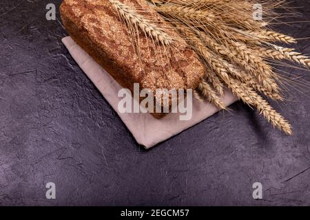 Rustic sourdough bread with crispy crust. Rye bread on dark background. Stock Photo