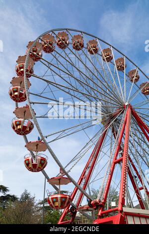 red giant wheel in front of a blue summer sky during the day, no people sitting in the gondolas, the festival starts in the evening when it gets dark Stock Photo