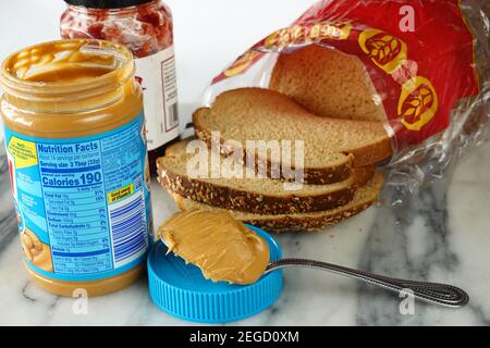Peanut butter nutrition facts, ingredients and calories label on a jar of skippy peanut butter and a jar of raspberry jelly or raspberry jam Stock Photo