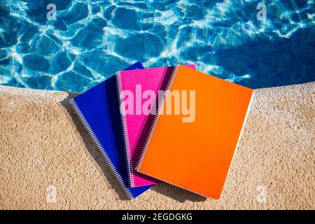 colored notebooks next to a pool Stock Photo