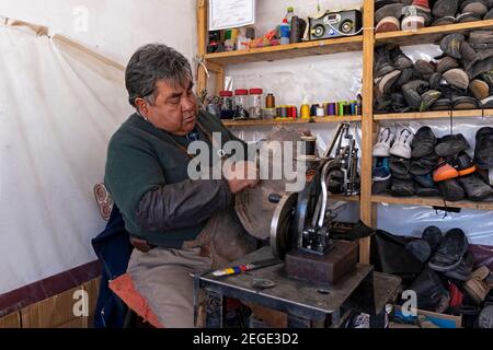 Old-fashioned Bolivian shoemaker with old sewing machine mending shoes in market stall in the city Uyuni, Antonio Quijarro Province, Potosí, Bolivia Stock Photo