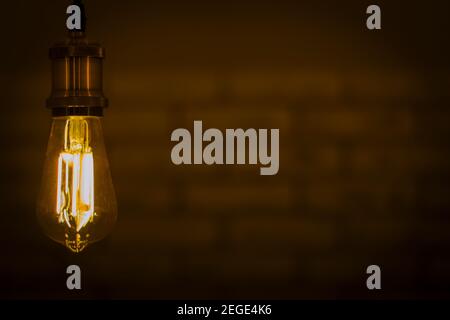Led lamp shining warm light in dark wallbrick background. Light bulb shine in darkness Stock Photo