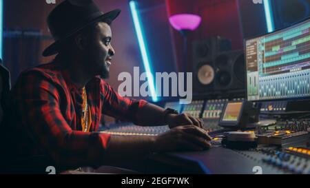 Stylish Male Audio Engineer Working in Music Recording Studio, Uses Mixing Board, Software to Create Modern Hit Song. Creative Artist Musician Working Stock Photo