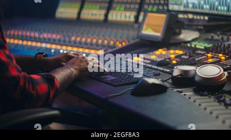 Music Creator, Musician, Artist Works in the Music Record Studio, Uses Surface Control Desk Equalizer Mixer. Buttons, Faders, Sliders to Broadcast Stock Photo
