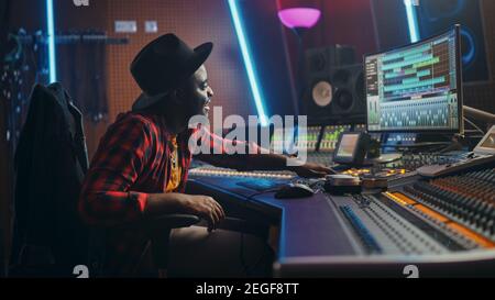 Portrait of Audio Engineer Working in Music Recording Studio, Uses Mixing Board Create Modern Sound. Successful Black Artist Musician Working at Stock Photo