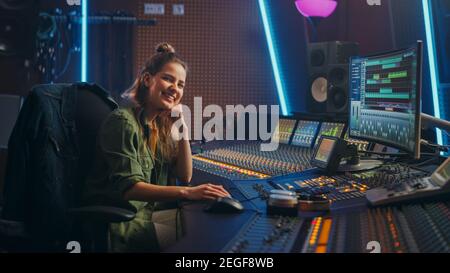 Stylish female audio engineer, producer works in music recording studio ...