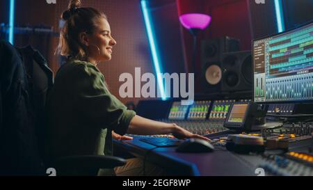 Stylish female audio engineer, producer works in music recording studio ...