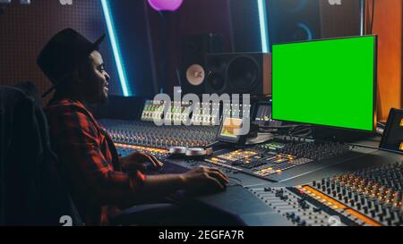 Stylish Audio Engineer Producer Working in Music Record Studio, Uses Green Screen Computer, Mixer Board Equalizer to Create New Hit Track and Song Stock Photo