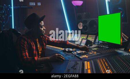 Stylish Audio Producer Working In Music Record Studio Uses Green Screen Pc  Mixer Board Equalizer And Control Desk To Create New Hit Track And Song  Creative Black Artist Musician Side View Portrait
