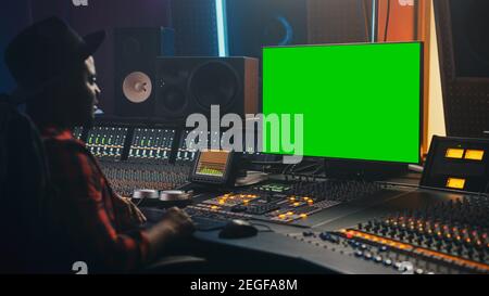 Portrait of Stylish Audio Engineer Producer Working in Music Record Studio, Uses Green Screen Computer, Mixer Board, Control Desk to Create New Song Stock Photo