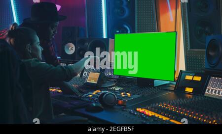 Producer and Audio Engineer Working together in Music Record Studio on a New Album, Use Green Screen Computer, Control Desk for Mixing and Creating Stock Photo
