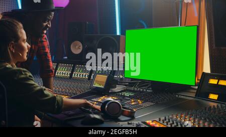 Producer and Audio Engineer Working together in Music Record Studio on a New Album, Use Green Screen Computer, Control Desk for Mixing and Creating Stock Photo
