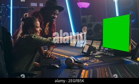 Producer and Audio Engineer Working together in Music Record Studio on a New Album, Use Green Screen Computer, Control Desk for Mixing and Creating Stock Photo