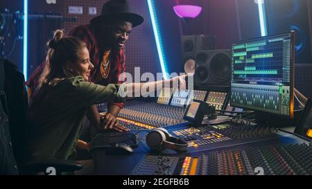 Producer and Professional Audio Engineer Working together in Music Recording Studio on a New Album, Talk, Use Control Desk Equalizer, Mixing Board and Stock Photo