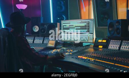 Portrait of Audio Engineer Working in Music Recording Studio, Uses Mixing Board Create Modern Sound. Successful Black Artist Musician Working at Stock Photo