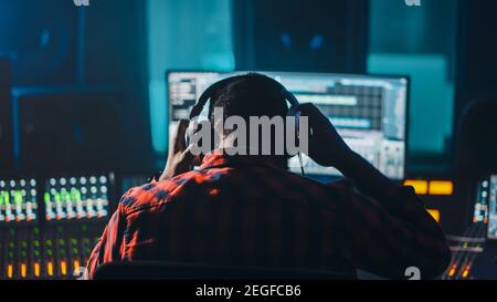 Stylish Artist, Musician, Audio Engineer, Producer Takes Place at His Control Desk in Music Record Studio, Uses Computer Screen show User Interface of Stock Photo