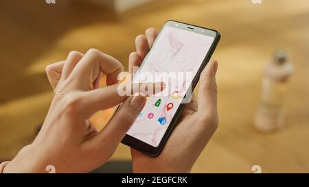 Close-up POV: Woman Uses Smartphone. She Uses Gesture and Taps on the Screen. The Background is Blurred with Yellow Colors. Concept of Using Stock Photo