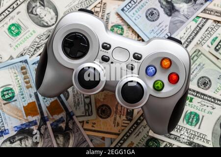 Silver wireless gamepad on dollar bills Stock Photo