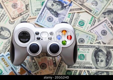 Silver wireless gamepad on dollar bills Stock Photo