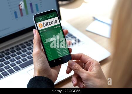 ROSARIO, ARGENTINA - FEBRUARY 17, 2021: Bitcoin chart in a screen of mobile phone. Business woman with smartphone in her hands. Virtual money investme Stock Photo