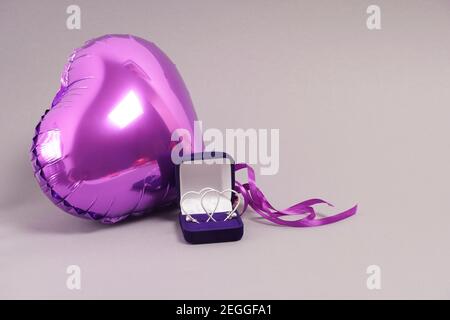 a valentine's gift. Balloon and earrings in the shape of the heart in a blue box on a yellow background Stock Photo