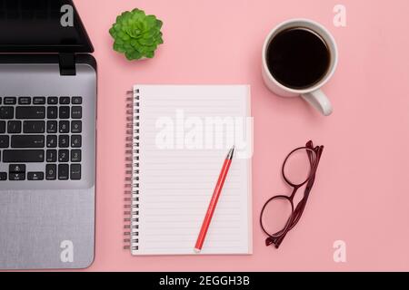flat lay, view from the top of the office desk table. Working space notepad, laptop, phone and coffee cup on a pink background. high quality Stock Photo