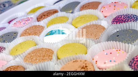 pasta of different colors on the counter in a pastry shop or store. Color background Stock Photo
