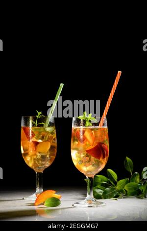 Peach fresh tea with ice, peach summer mocktail on a black background. Amber wine, sangria with peach and mint, close up and copy space Stock Photo