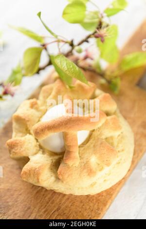 Homemade sweet Italian Easter Bread Rings with eggs called puddica in Puglia, on an old wooden cutten board with spring twig, close-up. Stock Photo