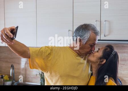 Old couple taking a selfie while kissing. Stock Photo