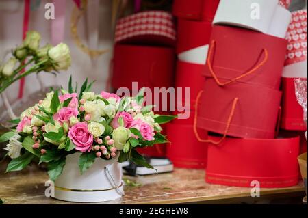 Flower box with pink and white roses on the table, red heart-shape boxes on the table Stock Photo