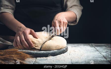 The cook prepares a dish of dough. Slicing dough on a black background. Stock Photo