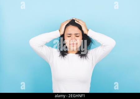 Young brunette woman suffers headache and complains with her hands Stock Photo